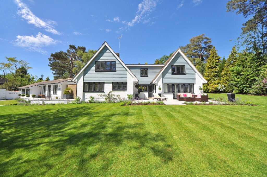 white and gray wooden house near grass field and trees